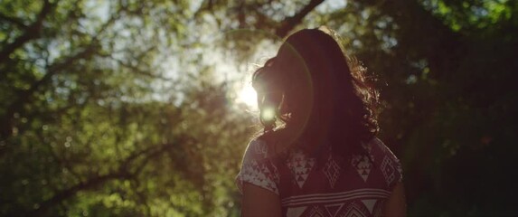 	Girl walks through evening woods with sun flare in slow motion