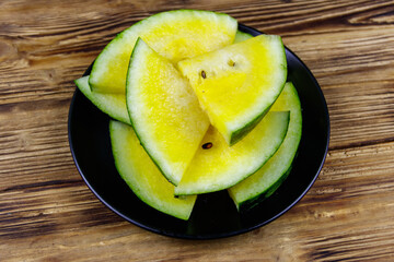 Fresh ripe sliced yellow watermelon in a plate on a wooden table. Top view