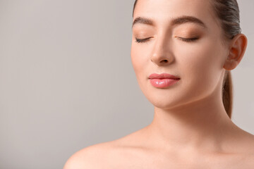 Young woman with acne problem on light background