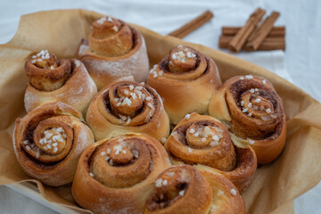 Cinnamon rolls with sugar frosting. With cinnamon sticks and spices, wooden background