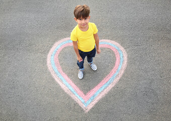 Little boy standing on chalk drawing of heart outdoors