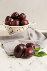 Tasty sweet plums on white table