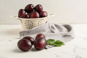 Tasty sweet plums on white table