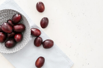 Basket with tasty sweet plums on white background