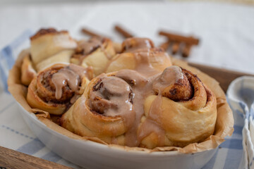 Cinnamon rolls with sugar frosting. With cinnamon sticks and spices, wooden background