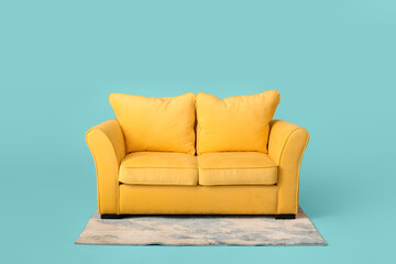 Stylish sofa and carpet on color background