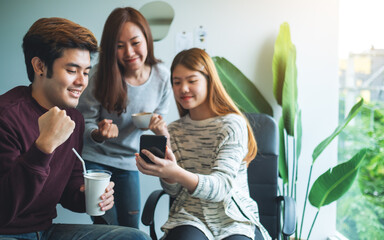 A group of young people having fun and celebrating while watching on mobile phone together