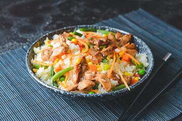 Bowl with tasty fried rice on dark background