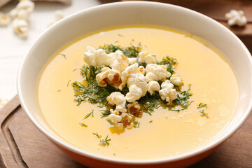 Bowl with tasty popcorn soup on table, closeup