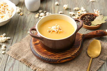 Pot with tasty popcorn soup on table