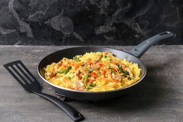 Frying pan with tasty rice on dark background