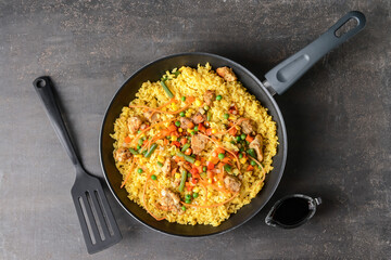 Frying pan with tasty rice on dark background