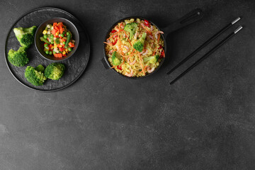 Frying pan with tasty rice and vegetables on dark background