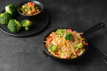 Frying pan with tasty rice and vegetables on dark background