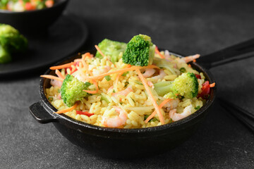 Frying pan with tasty rice and vegetables on dark background