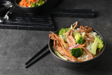 Bowl with tasty fried rice on dark background