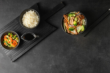 Bowls with tasty rice and vegetables on dark background