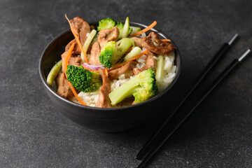 Bowl with tasty fried rice on dark background