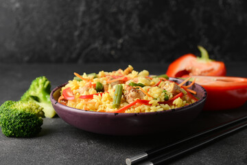 Bowl with tasty fried rice on dark background