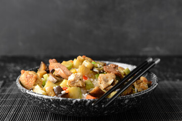 Bowl with tasty fried rice on dark background