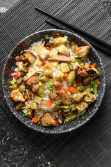 Bowl with tasty fried rice on dark background