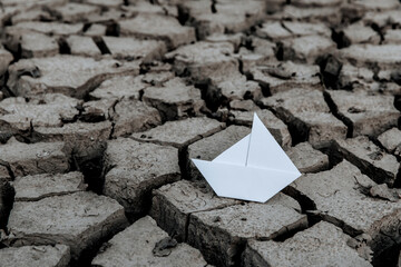 Paper boat on dry lake, Concept drought and crisis environment.