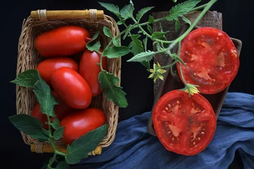 Foto auf Glas Rijpe tomaten op een zwarte achtergrond.Heerlijk vegetarisch eten. © NADEZHDA