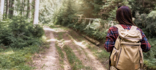 Back view woman walks with backpacker in the forest. Travel lifestyle concept