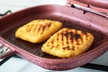 Schnitzel fried on the grill pan. Two pieces of Cordon Bleu with ham and cheese in a pan.
