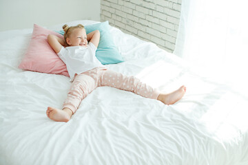 Little girl in bed with white linen. A child at home in the morning wakes up in his room. High quality photo.