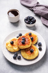 Fritters of cottage cheese with blueberries. Cheese curd cheesecakes, pancakes on a grey concrete background. Copy space.