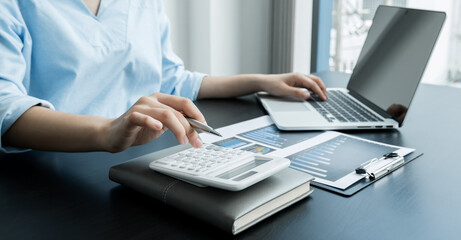 The woman's hand uses a calculator. Calculate the financial graph that shows the results to summarize the Summary of the overall balance in the office