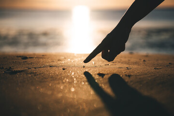 Human hand point to tiny cute crab on the beach sand © dodotone