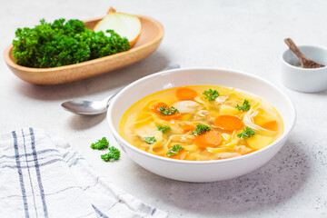 Homemade chicken soup with noodles and vegetables in white bowl, white background. Healthy warm comfortable food.