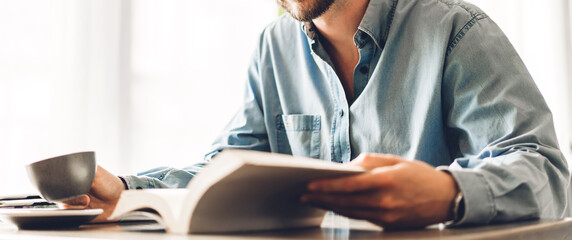Handsome hipster man relaxing read the paper book work study and looking at page magazine while...