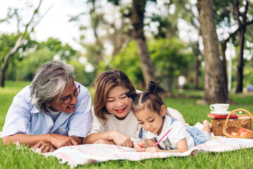 Portrait of happy grandfather with grandmother and little cute girl enjoy relax in summer park.Young girl with their laughing grandparents smiling together.Family and togetherness