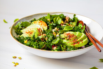 Healthy salad with kale, quinoa, nuts and avocado in white bowl. Healthy vegan food concept.