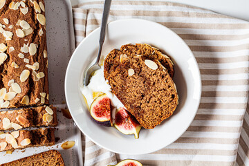 Portion of banana bread with yogurt and figs, white background.