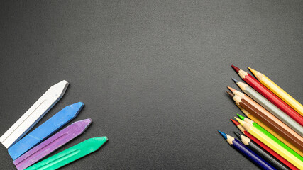 Study table. Education accessories with colorful pencils, chalk, brushes on dark school blackboard. Banner Concept Back To School.