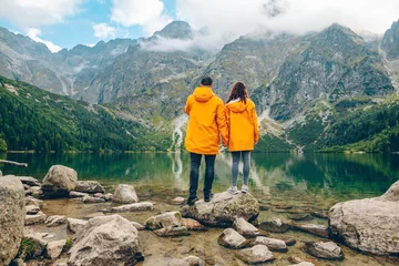Printed kitchen splashbacks Tatra Mountains man with woman in yellow raincoat at sunny autumn day looking at lake in tatra mountains