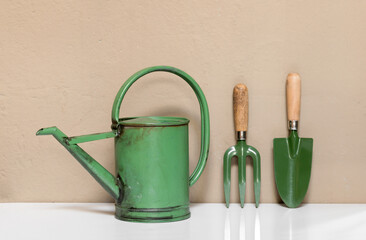 Set of small green garden tools against a wall