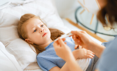 Obraz na płótnie Canvas Woman measuring temperature of small sick girl