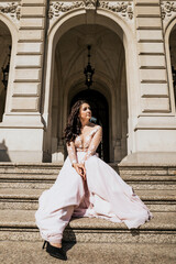 Naklejka premium Beautiful attractive woman stand on stairs in pink dress and look away