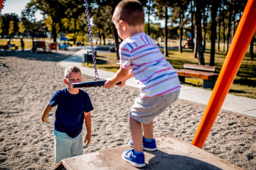 Brothers playing in public park during summer day