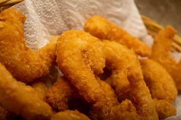 Atlantic shrimps fried in batter on a white paper napkin in a wicker basket. Close up.