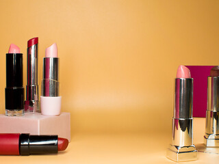 Red and pink lipsticks on podium, copy space, place for text. Cosmetics make up beauty product. Trendy cosmetic design.