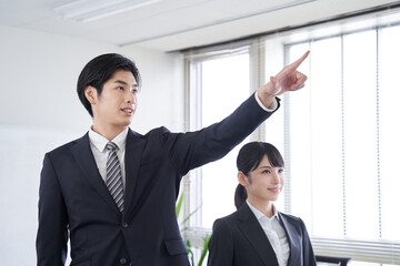 オフィスで目標に向かって指をさす日本人男性ビジネスマン
