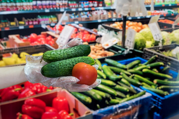 seller in gloves sells fresh vegetables. man gives dollars for groceries in the supermarket.