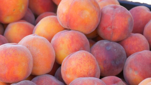 Close up view of ripe beautiful large fresh pink peaches fruits on a street market counter or a vegetable store in summer