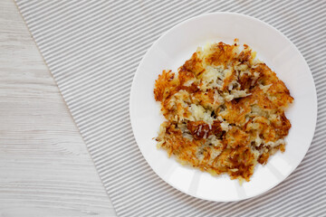 Homemade Fried Hashbrowns on a white plate, top view. Copy space.